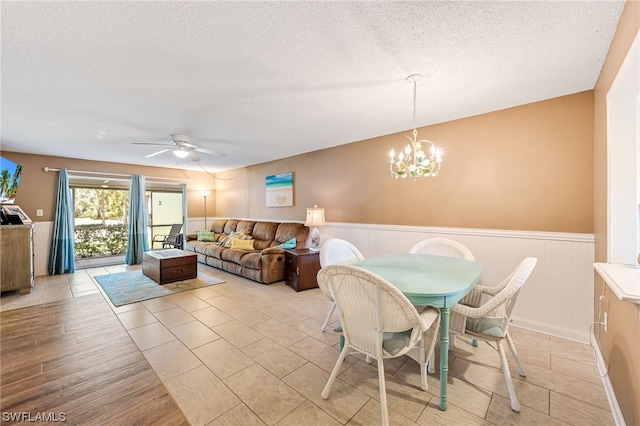 dining area featuring a textured ceiling, ceiling fan with notable chandelier, and light tile floors