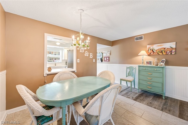 tiled dining area with an inviting chandelier, a textured ceiling, and sink