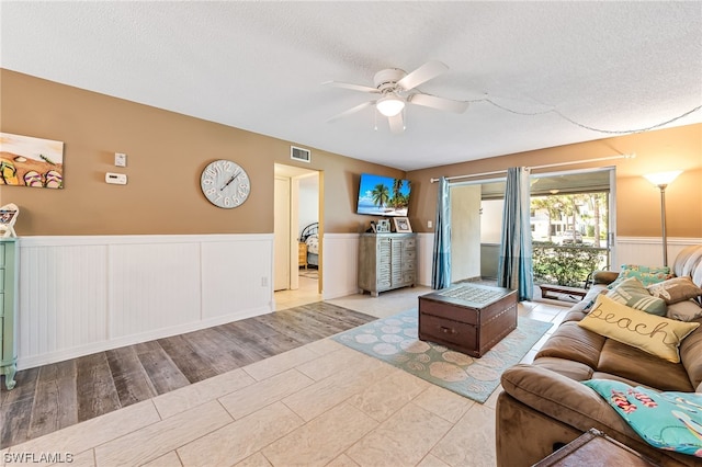 living room with light tile flooring, ceiling fan, and a textured ceiling