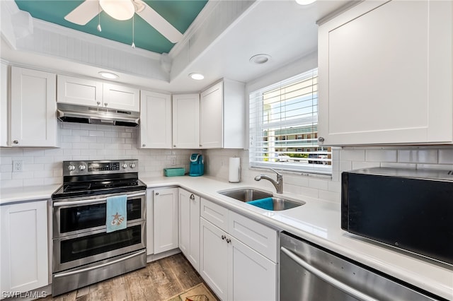 kitchen with light wood-type flooring, ceiling fan, appliances with stainless steel finishes, and white cabinetry