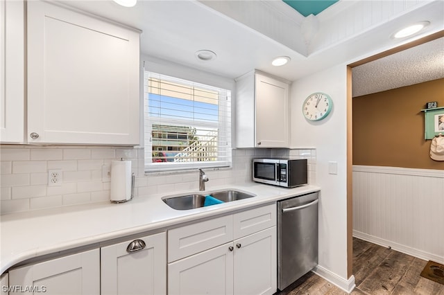 kitchen with sink, dark hardwood / wood-style flooring, white cabinets, appliances with stainless steel finishes, and tasteful backsplash