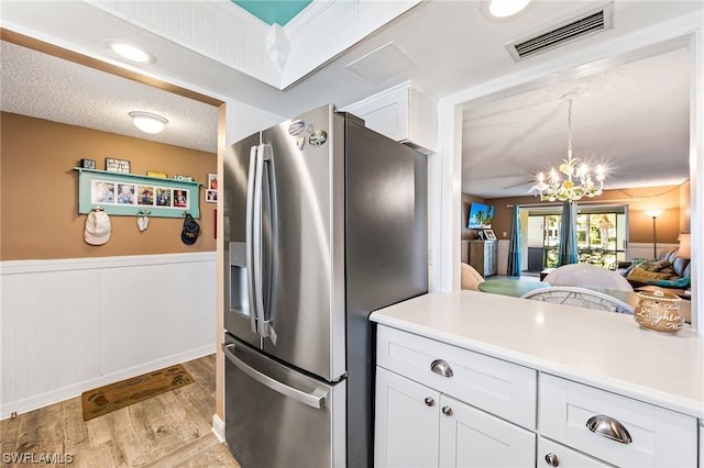 kitchen featuring white cabinets, light hardwood / wood-style floors, a notable chandelier, a textured ceiling, and stainless steel refrigerator with ice dispenser