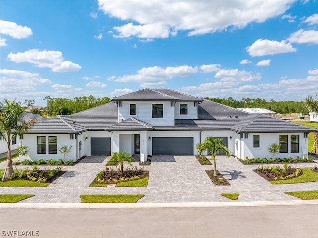 view of front of home with a tile roof, decorative driveway, and a garage