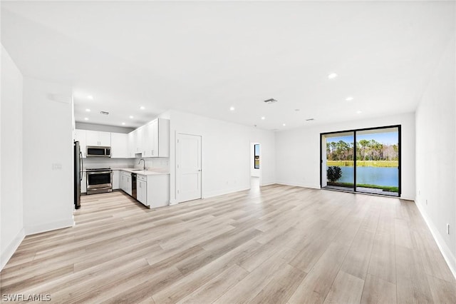 unfurnished living room featuring sink and light hardwood / wood-style floors