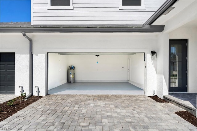 garage featuring water heater and decorative driveway