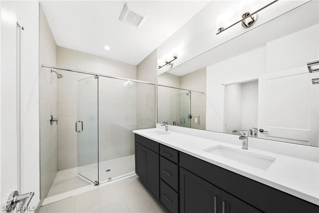 bathroom with a shower stall, double vanity, visible vents, and a sink