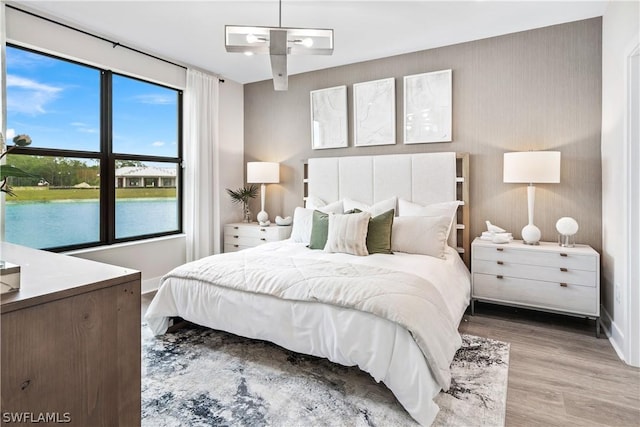 bedroom featuring wood-type flooring, a water view, and multiple windows