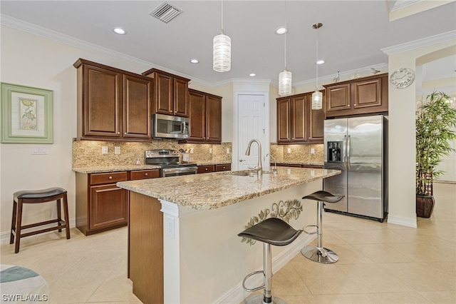 kitchen with sink, stainless steel appliances, a kitchen breakfast bar, a center island with sink, and decorative light fixtures