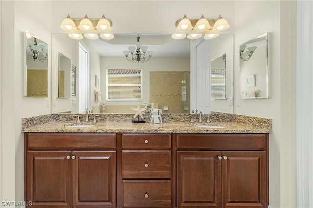 bathroom featuring tiled shower, vanity, and a notable chandelier