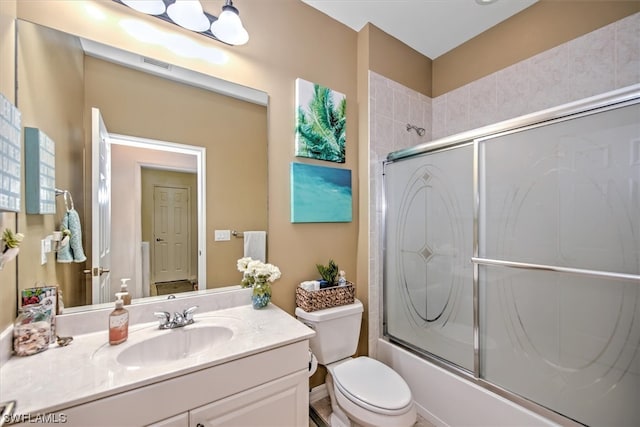 full bathroom with toilet, vanity, and bath / shower combo with glass door