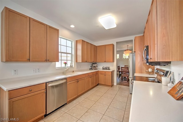 kitchen featuring hanging light fixtures, light tile floors, appliances with stainless steel finishes, and sink