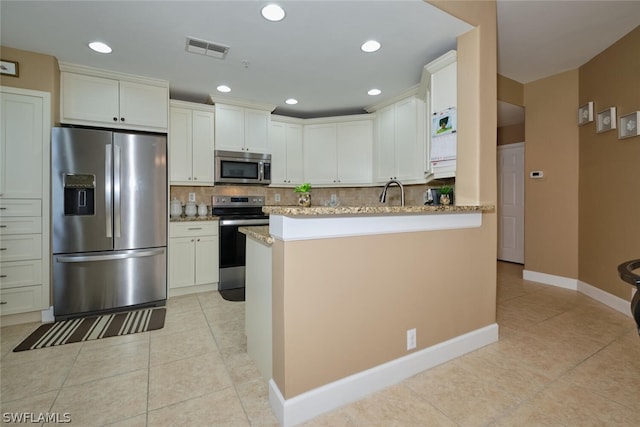 kitchen with light stone counters, kitchen peninsula, stainless steel appliances, light tile patterned floors, and tasteful backsplash