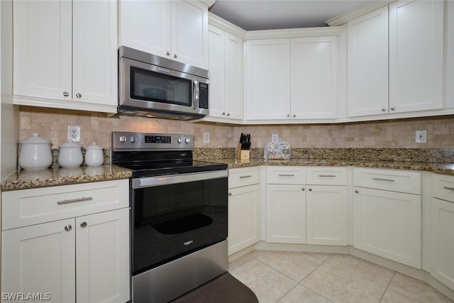 kitchen featuring stainless steel appliances, dark stone counters, white cabinets, and tasteful backsplash