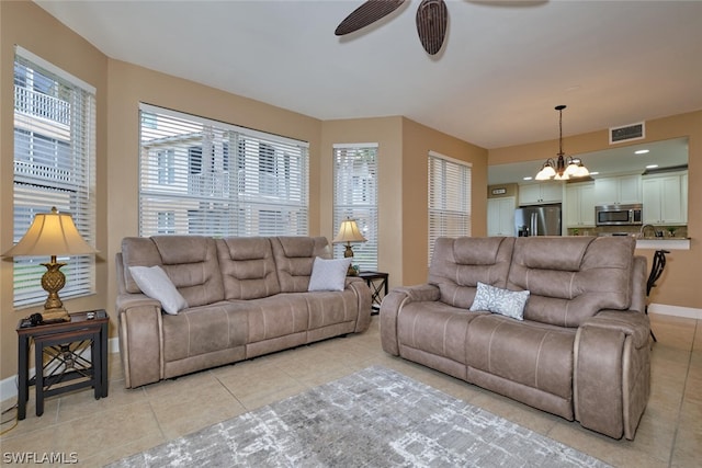 tiled living room with ceiling fan with notable chandelier