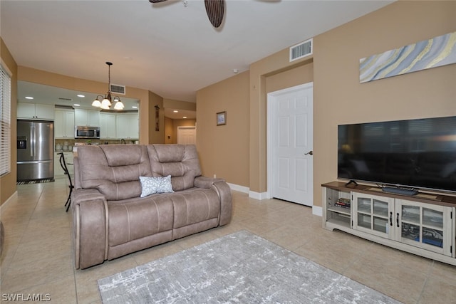 tiled living room featuring ceiling fan with notable chandelier