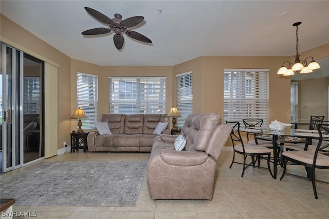 living room with ceiling fan with notable chandelier, a healthy amount of sunlight, and light tile patterned floors