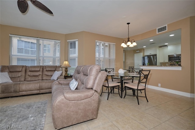 tiled living room featuring ceiling fan with notable chandelier and a wealth of natural light