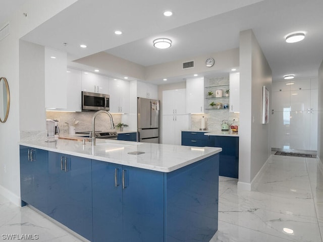 kitchen featuring white cabinetry, blue cabinetry, appliances with stainless steel finishes, and kitchen peninsula