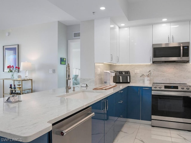 kitchen featuring white cabinetry, blue cabinetry, appliances with stainless steel finishes, and light stone countertops