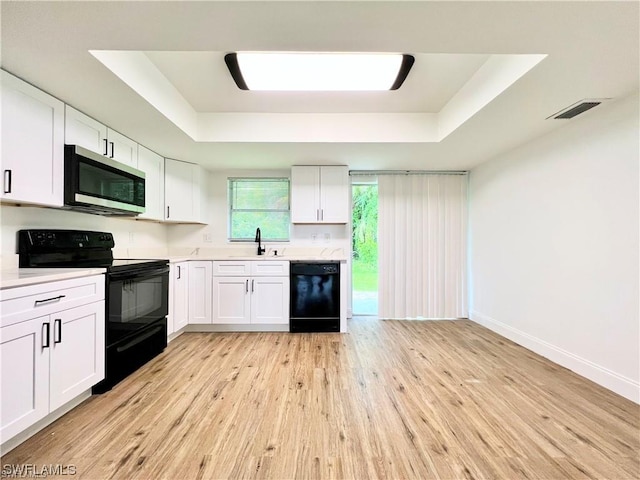 kitchen featuring a tray ceiling, white cabinets, and black appliances