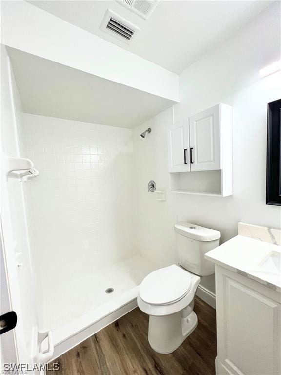 bathroom with walk in shower, hardwood / wood-style flooring, vanity, and toilet