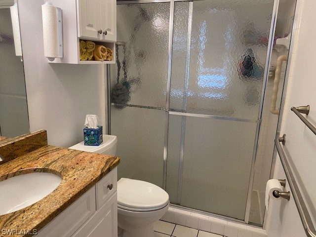 bathroom with tile patterned floors, a shower with door, toilet, and vanity