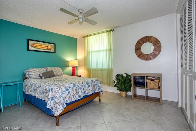 tiled bedroom with a textured ceiling, a closet, and ceiling fan