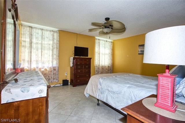 bedroom featuring ceiling fan, light tile patterned flooring, and a textured ceiling