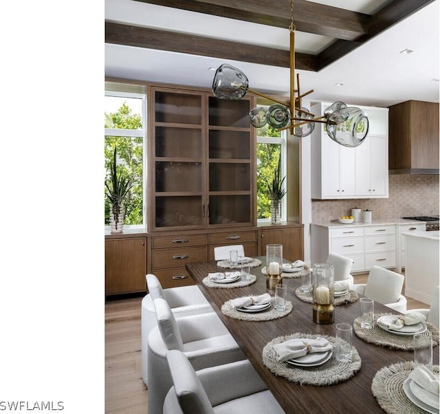 dining space featuring beamed ceiling and light hardwood / wood-style flooring