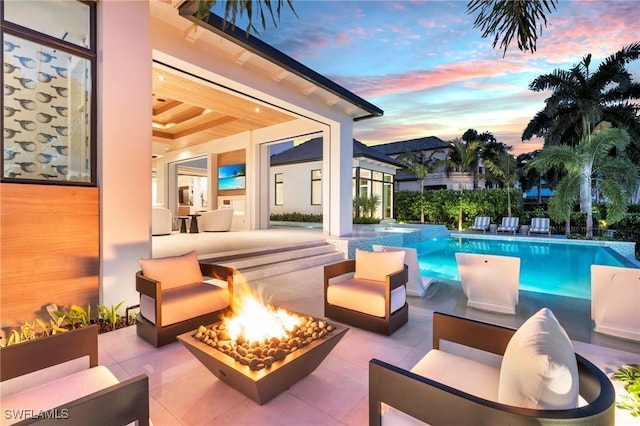 pool at dusk featuring an outdoor hangout area and a patio