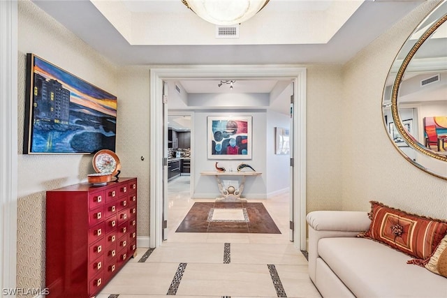 corridor featuring a tray ceiling, visible vents, and baseboards