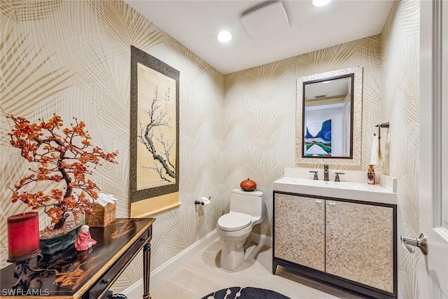 half bath with recessed lighting, vanity, toilet, and wallpapered walls