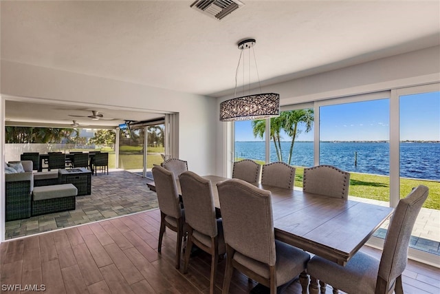 dining area featuring dark hardwood / wood-style floors, a healthy amount of sunlight, and a water view