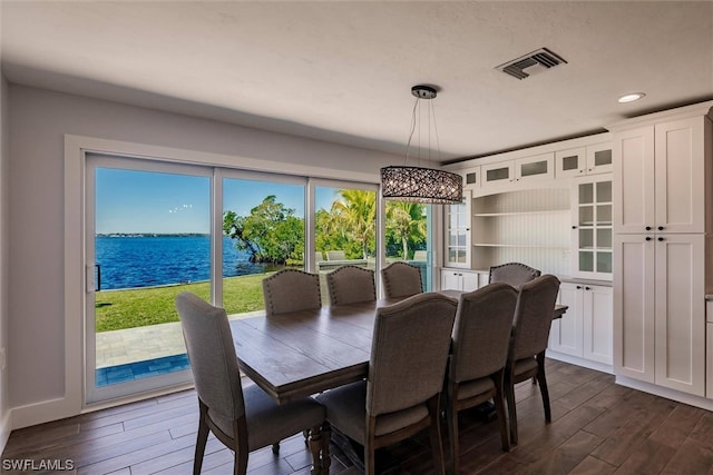 dining area with a water view and dark wood-type flooring