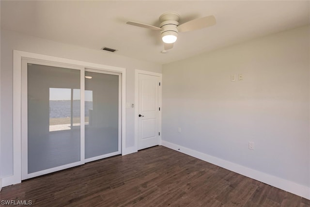 unfurnished room featuring a water view, ceiling fan, and dark hardwood / wood-style floors