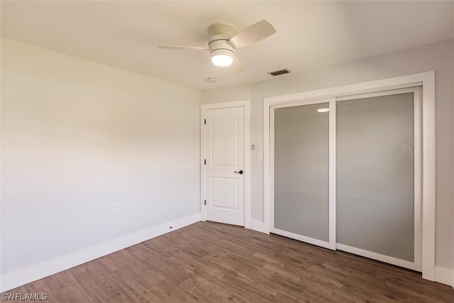 unfurnished bedroom featuring a closet, ceiling fan, and dark wood-type flooring