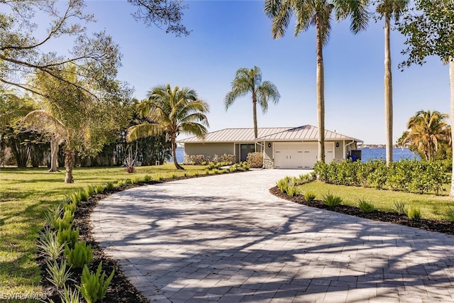 ranch-style home with a front lawn, a garage, and a water view