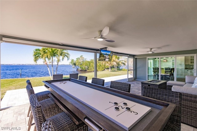 view of patio / terrace featuring a water view, ceiling fan, and an outdoor living space with a fire pit