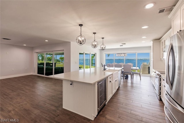 kitchen with an island with sink, pendant lighting, plenty of natural light, and white cabinetry