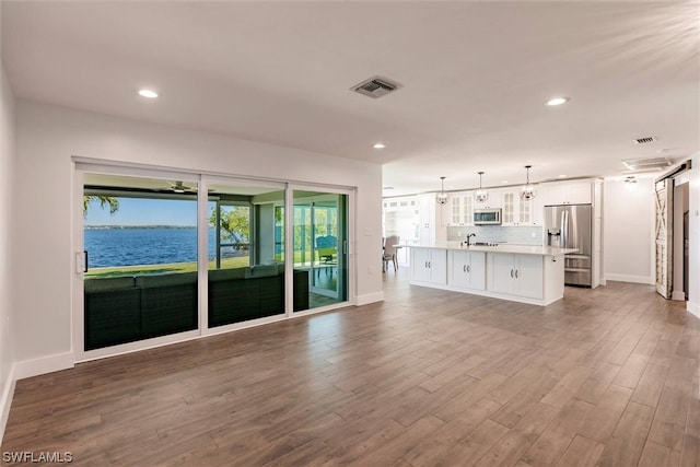 unfurnished living room with a water view, wood-type flooring, and sink