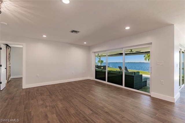 empty room featuring dark wood-type flooring and a water view