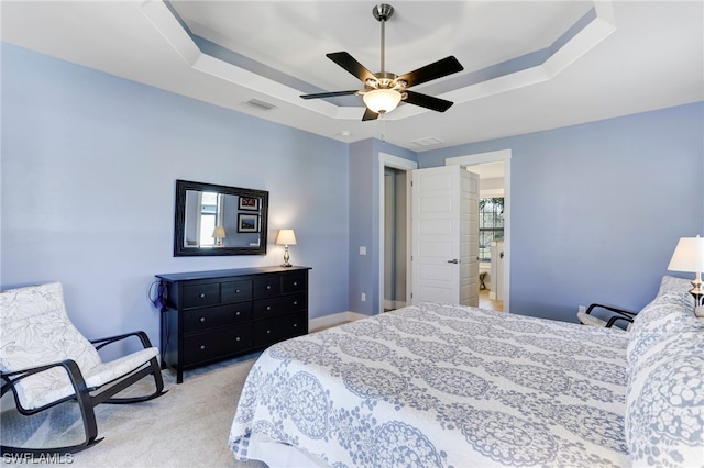 carpeted bedroom featuring connected bathroom, ceiling fan, and a tray ceiling