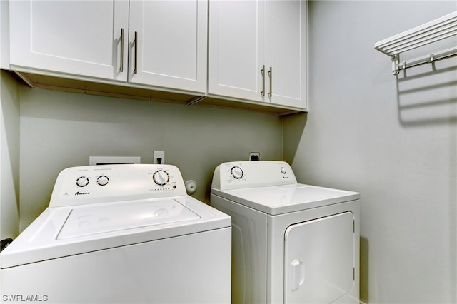 clothes washing area featuring washing machine and dryer and cabinets