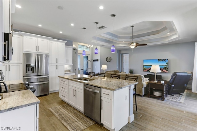 kitchen featuring white cabinets, a center island with sink, sink, and ceiling fan with notable chandelier