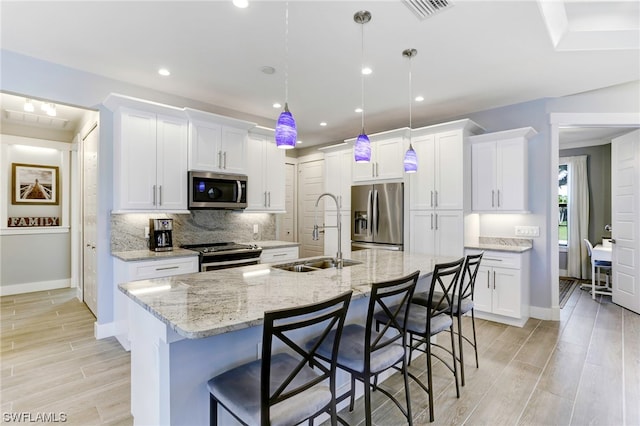 kitchen with stainless steel appliances, decorative light fixtures, a breakfast bar, and sink