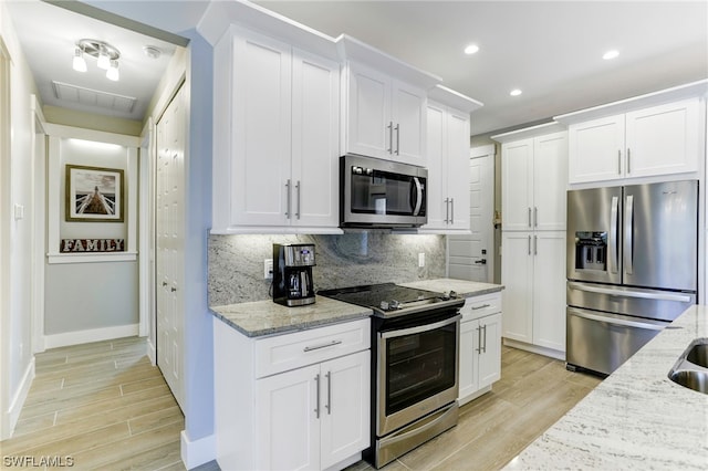 kitchen featuring appliances with stainless steel finishes, white cabinetry, and tasteful backsplash