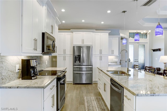 kitchen with french doors, sink, a raised ceiling, appliances with stainless steel finishes, and light hardwood / wood-style flooring