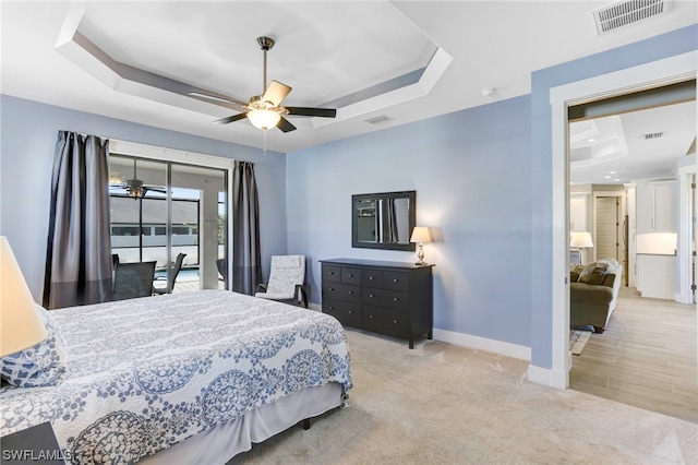 bedroom with a tray ceiling, ceiling fan, and light wood-type flooring