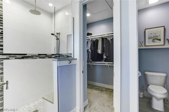 bathroom featuring a tile shower and toilet