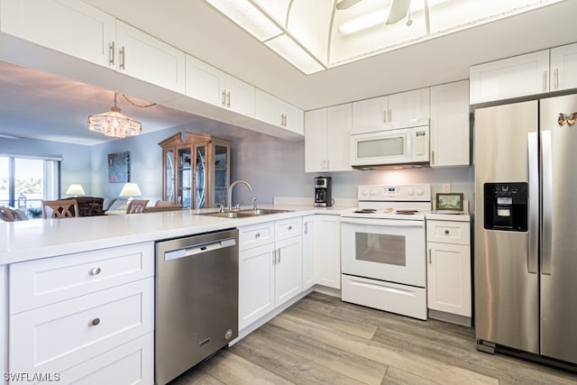 kitchen featuring appliances with stainless steel finishes, sink, light hardwood / wood-style floors, white cabinetry, and decorative light fixtures